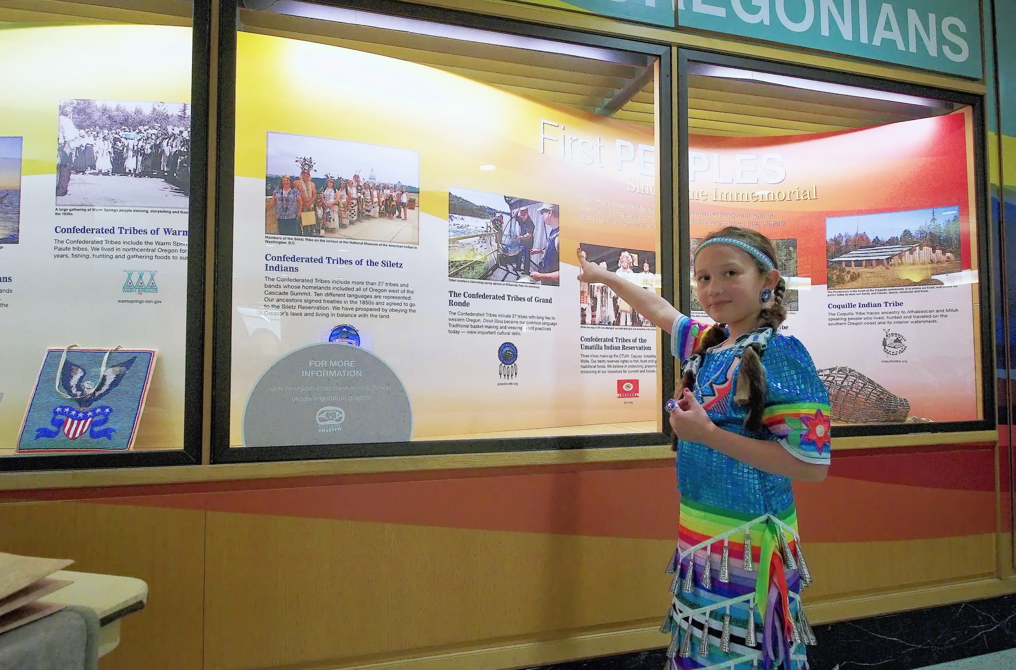 Young tribal member points at exhibit of her nation.