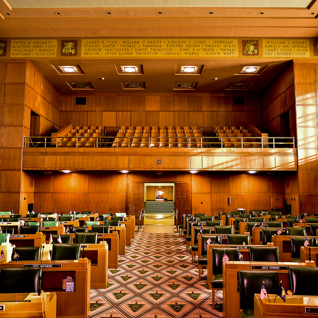 The Oregon House of Representatives as seen from the center aisle, looking toward the Senate, featuring the capitol names above the chamber.