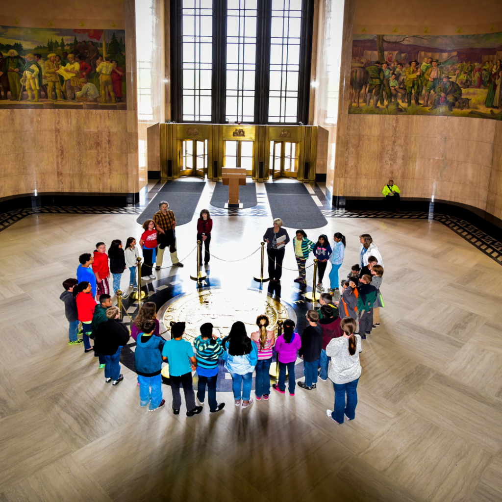 a group of children gathered around the Oregon State Seal inside the Capitol Rotunda